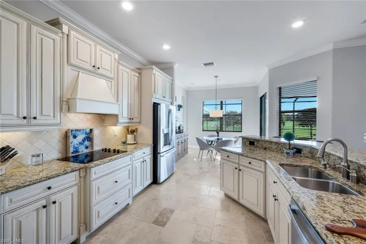 Gourmet kitchen with granite countertops, custom hood, built-in stovetop, French door refrigerator, eat-in kitchen with breakfast table overlooking your beautiful outdoor oasis!