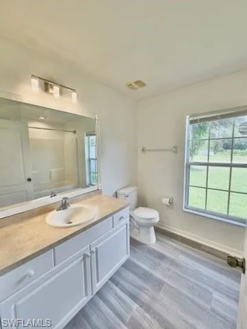 Bathroom featuring vanity, hardwood / wood-style floors, toilet, and walk in shower