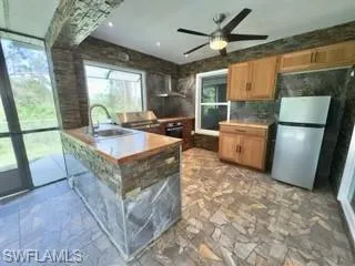 Kitchen with oven, sink, stainless steel fridge, ceiling fan, and extractor fan