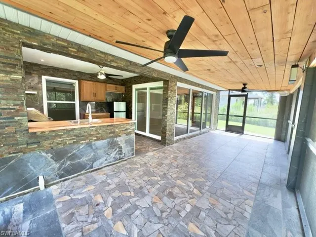 Unfurnished sunroom featuring wood ceiling, sink, and ceiling fan
