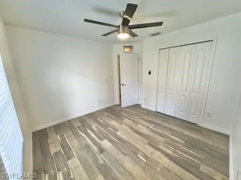 Unfurnished bedroom with a closet, hardwood / wood-style flooring, and ceiling fan