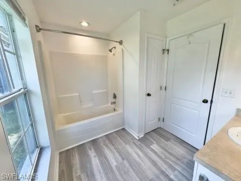 Bathroom featuring vanity, wood-type flooring, and shower / washtub combination