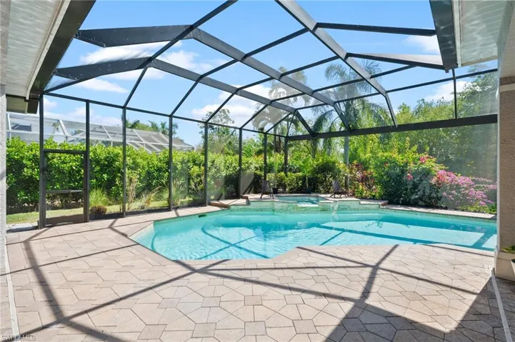 View of swimming pool featuring a patio, an in ground hot tub, and glass enclosure