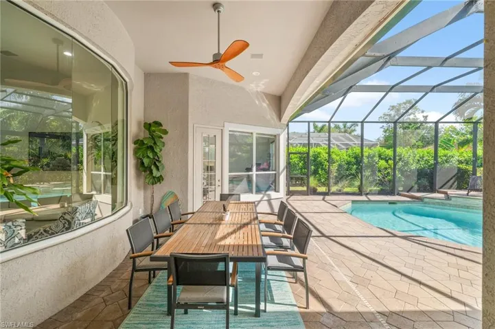 View of swimming pool with ceiling fan, a patio area, and glass enclosure