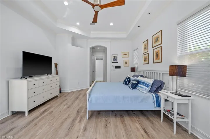 Bedroom with ornamental molding, a tray ceiling, and light wood-type flooring