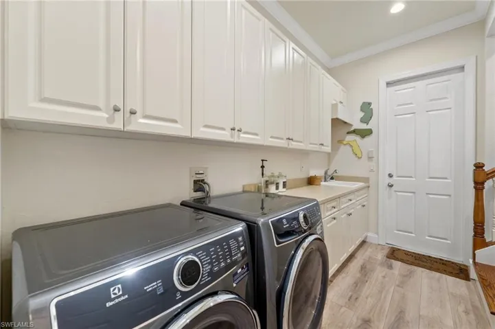Laundry room with sink, cabinets, independent washer and dryer, crown molding, and light hardwood / wood-style flooring