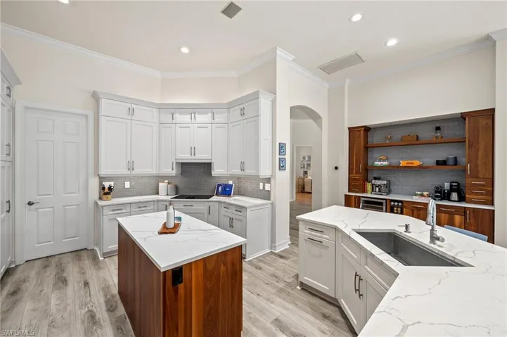 Kitchen with white cabinetry, light stone countertops, sink, and a kitchen island
