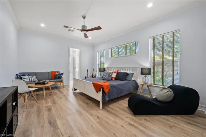 Bedroom with multiple windows, ornamental molding, light hardwood / wood-style floors, and ceiling fan