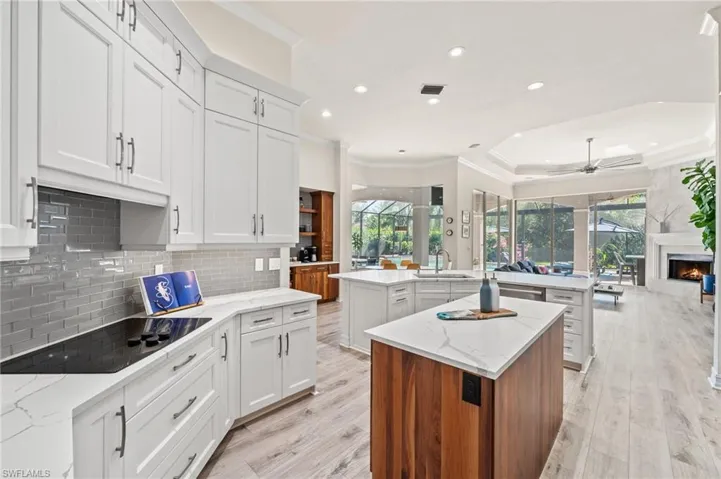 Kitchen featuring black electric stovetop, sink, white cabinets, and a kitchen island