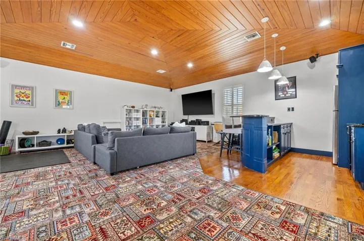 Living room featuring vaulted ceiling, hardwood / wood-style floors, and wooden ceiling
