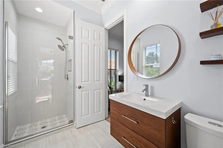 Bathroom featuring walk in shower, ornamental molding, vanity, and toilet