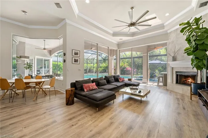 Living room featuring crown molding, ceiling fan, a premium fireplace, and light wood-type flooring