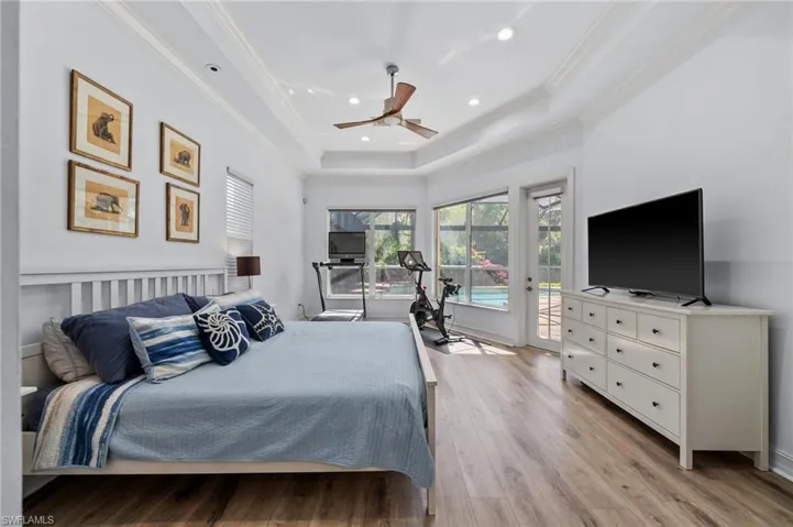 Bedroom with crown molding, access to exterior, a tray ceiling, and light wood-type flooring