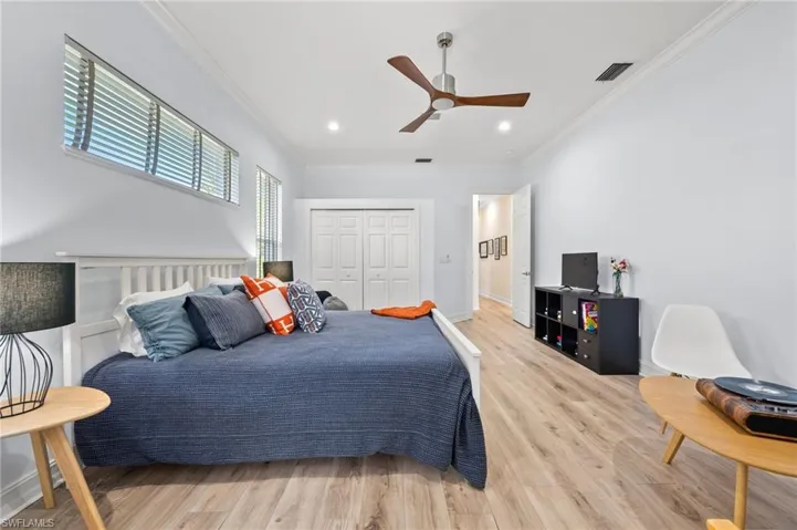 Bedroom with crown molding, hardwood / wood-style floors, ceiling fan, and a closet