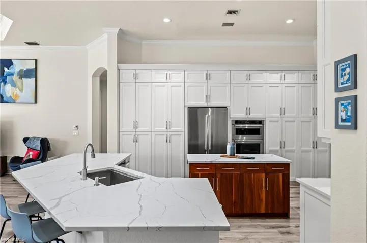 Kitchen featuring a kitchen bar, sink, a center island with sink, appliances with stainless steel finishes, and white cabinets
