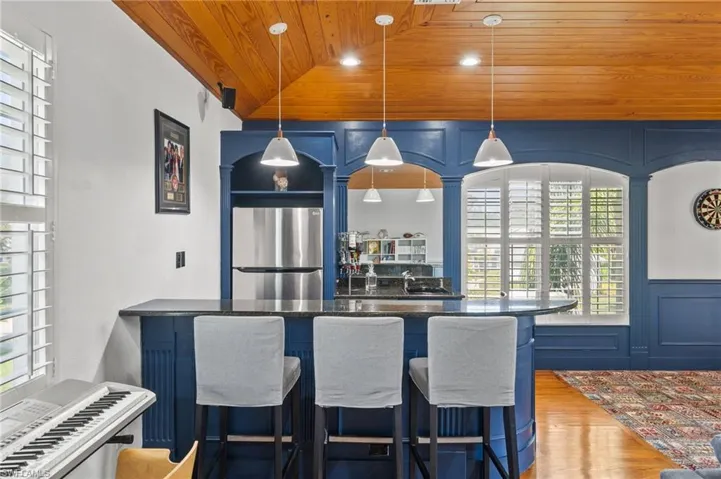 Kitchen featuring blue cabinetry, wooden ceiling, and stainless steel refrigerator