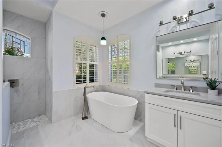 Bathroom with vanity, shower with separate bathtub, and tile walls