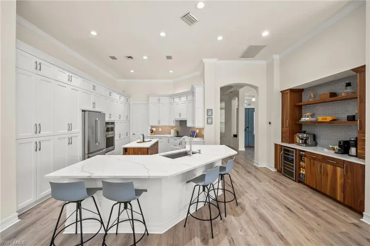 Kitchen with a breakfast bar, white cabinetry, sink, stainless steel appliances, and a center island with sink