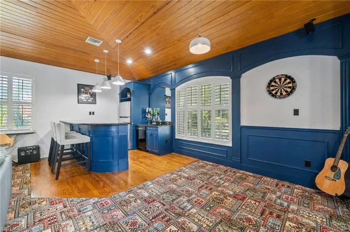Bar featuring a healthy amount of sunlight, blue cabinets, hanging light fixtures, and wooden ceiling