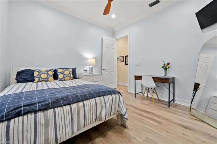 Bedroom with crown molding, ceiling fan, and wood-type flooring