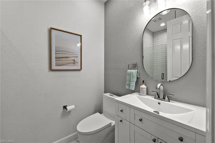 Bathroom featuring vanity, toilet, and a shower