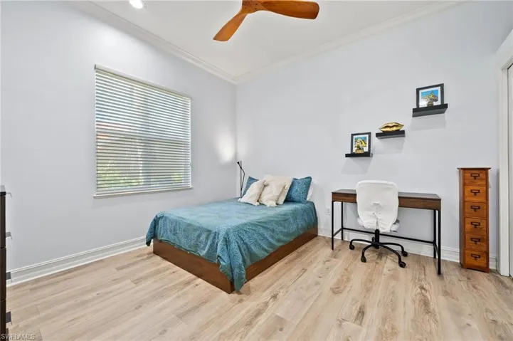 Bedroom with ornamental molding, ceiling fan, and light hardwood / wood-style flooring