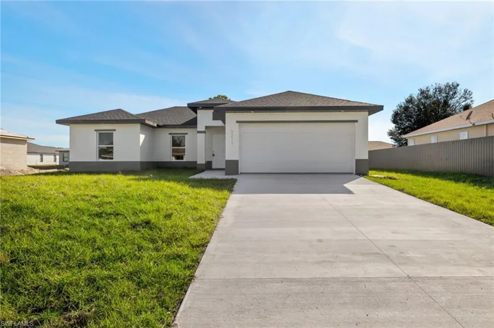 View of front facade featuring a garage and a front lawn