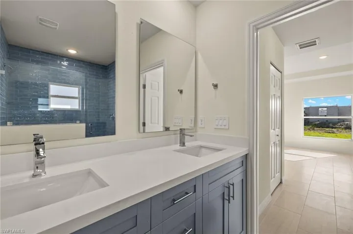 Bathroom featuring walk in shower, vanity, and tile patterned flooring