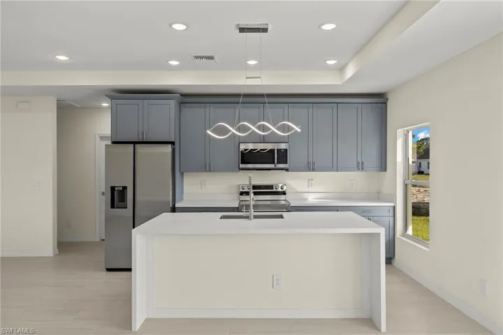 Kitchen with an island with sink, sink, gray cabinetry, and stainless steel appliances