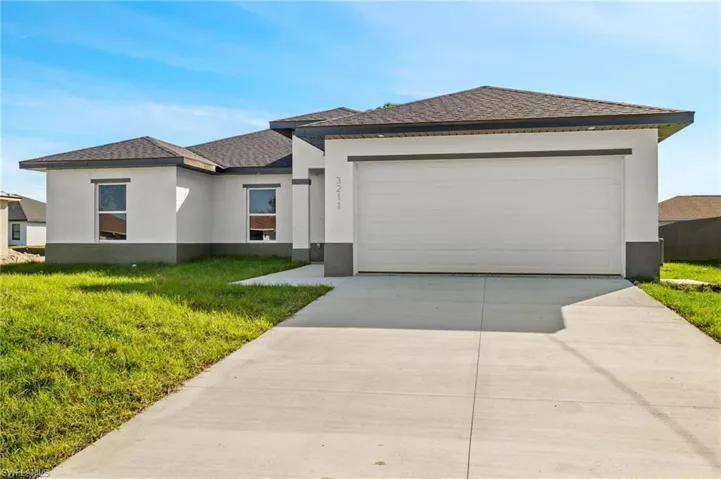 View of front facade featuring a front yard and a garage