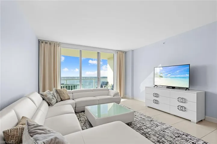 Living room with light tile patterned floors and floor to ceiling windows