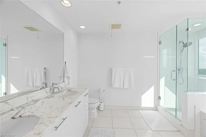 Bathroom featuring a stall shower, double vanity, recessed lighting, and light tile patterned flooring