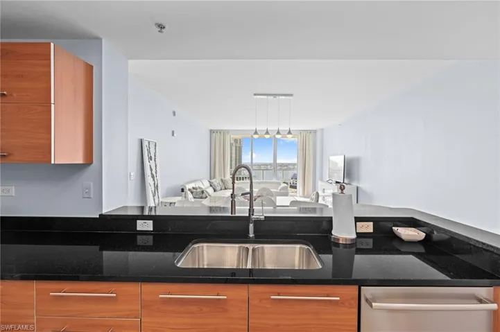 Kitchen with wood finish cabinets, open floor plan, dark stone counters, dishwasher, and modern cabinets