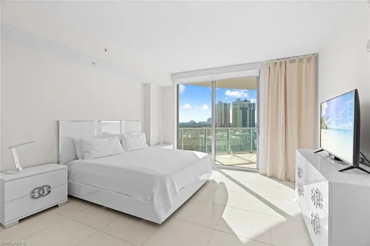 Bedroom featuring expansive windows, access to exterior, and light tile patterned floors