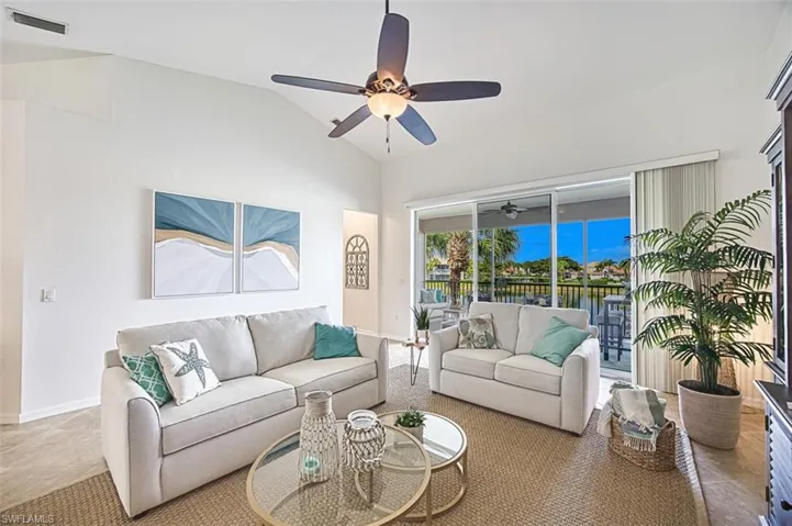 Living area featuring vaulted ceiling, tile patterned flooring, a water view, and ceiling fan