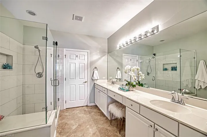 Bathroom featuring a shower stall and double vanity