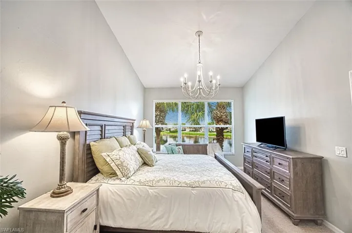 Carpeted bedroom featuring a chandelier and baseboards