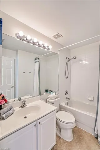 Full bath featuring shower / tub combo with curtain, vanity, and light tile patterned floors