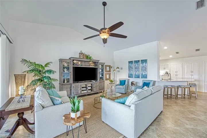 Living area featuring lofted ceiling, a ceiling fan, and light tile patterned floors