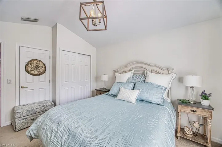 Carpeted bedroom featuring lofted ceiling, a closet, and a chandelier