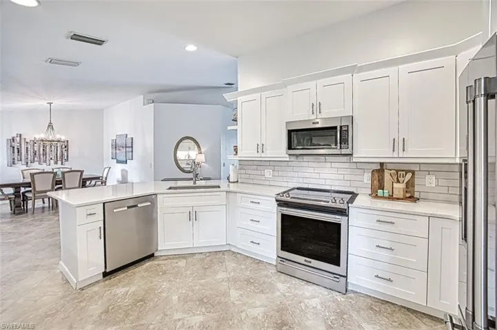 Kitchen featuring appliances with stainless steel finishes, white cabinets, hanging light fixtures, recessed lighting, and a peninsula