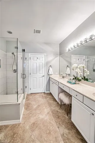 Full bath with double vanity and a shower stall