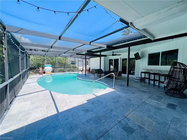 Outdoor pool featuring a sunroom, a lanai, a patio, and outdoor lounge area