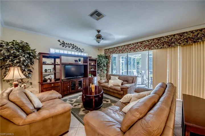 Living area featuring ceramic tile flooring, a built-in wooden media center, glass block accent windows, a ceiling fan, and sliding glass doors