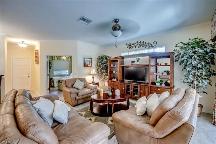 Living area featuring built-in wooden media cabinetry, transom window, ceiling fan with light fixture, and tile flooring