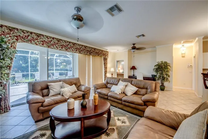 Open-concept living space featuring ceramic tile flooring, dual ceiling fans with integrated lighting, and expansive sliding glass doors