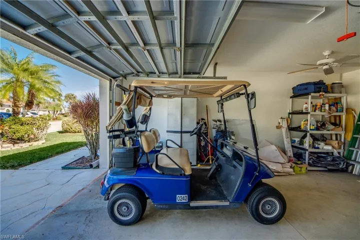 Enclosed garage featuring an overhead paneled door, integrated ceiling fan, and concrete flooring