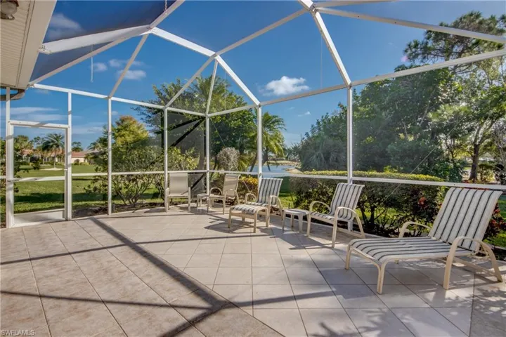 Screened-in lanai featuring white aluminum framing, large-format tile flooring, and water-front outdoor space