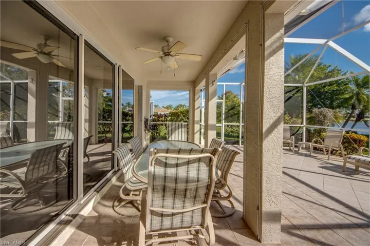 Screened-in lanai featuring tile flooring, a ceiling fan, and sliding glass wall panels