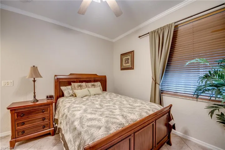Neutral wall palette featuring crown molding, tile flooring, and a ceiling fan